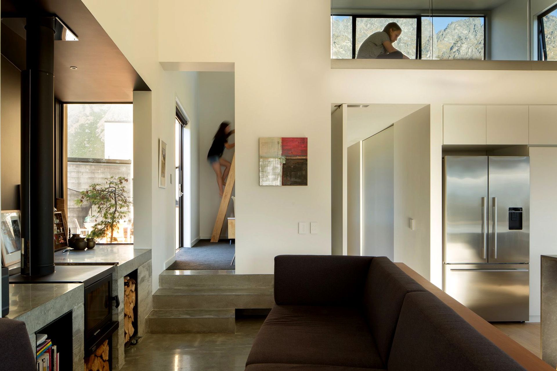 High windows draw sunlight into the mezzanine space and through into the main living area.