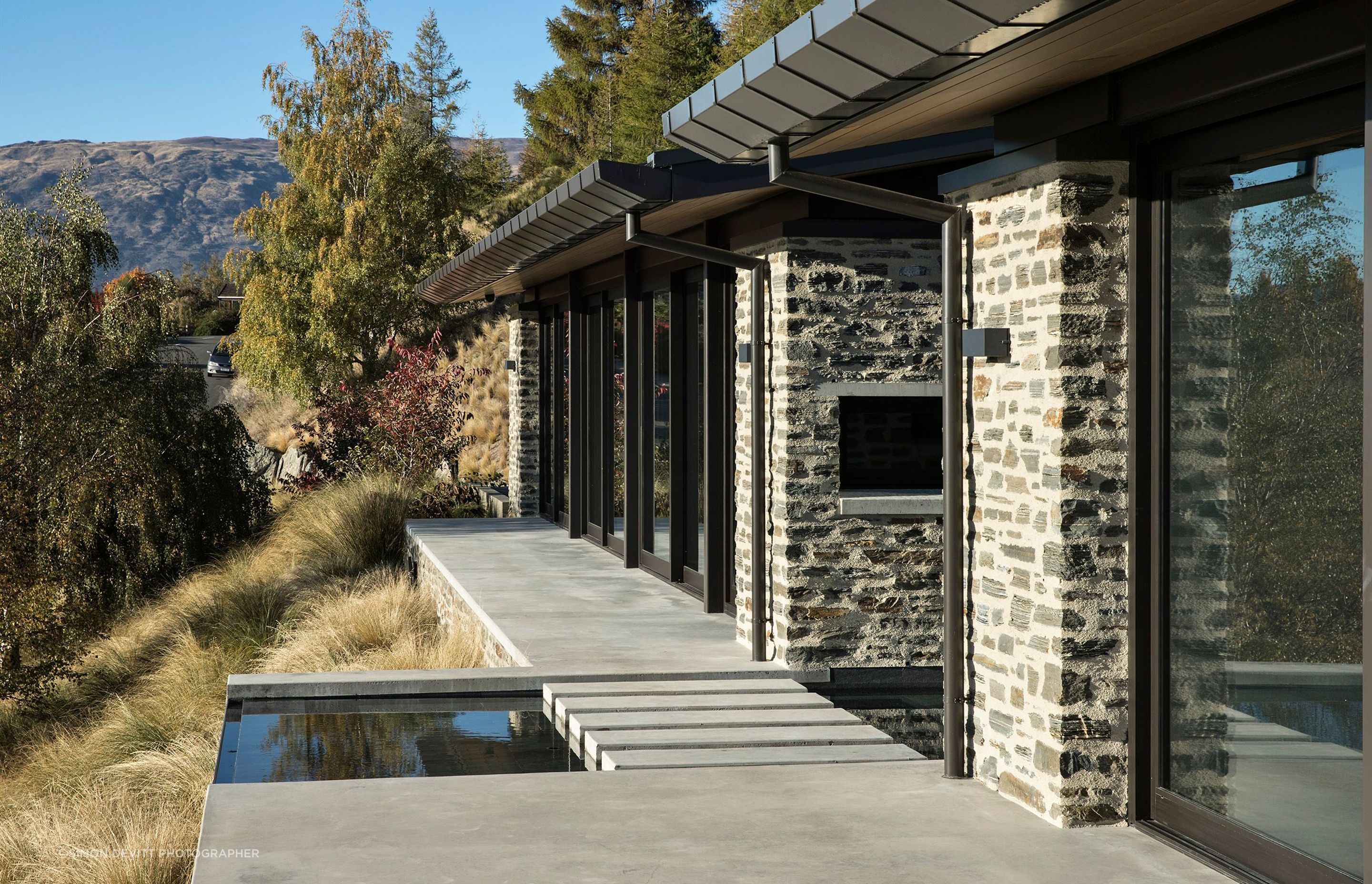 Constructed in local schist, Mt Aspiring House, by Mason &amp; Wales Architects, pays homage to the jaw-dropping views of Lake Wanaka and The Remarkables through full-height glazing and this linking pond between forms. Photograph by Simon Devitt.