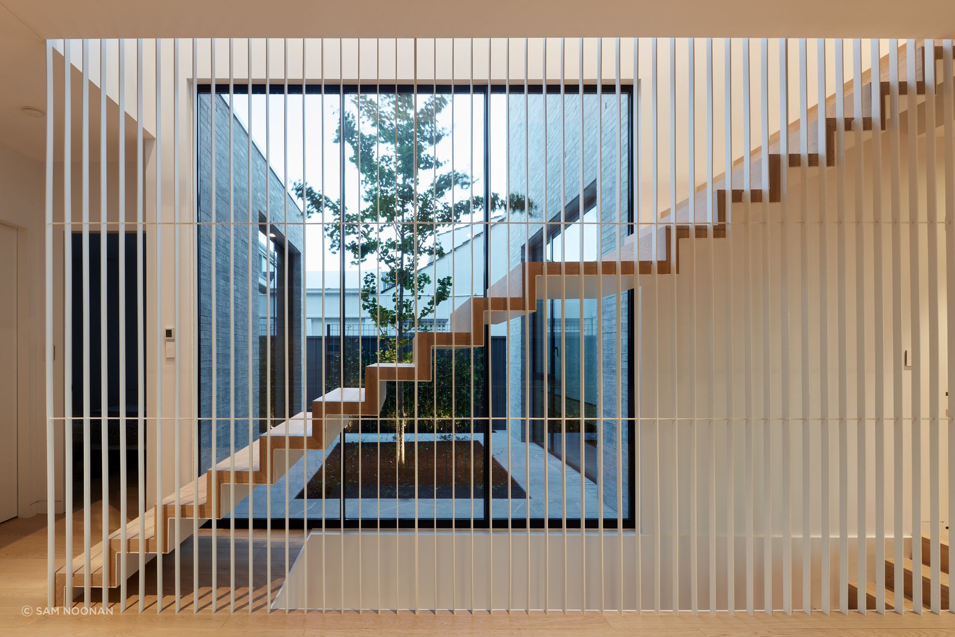 The suspended timber staircase with a battened steel balustrade lets the light flow through from the courtyard | Tennyson Residence by Enzo Caroscio Architects