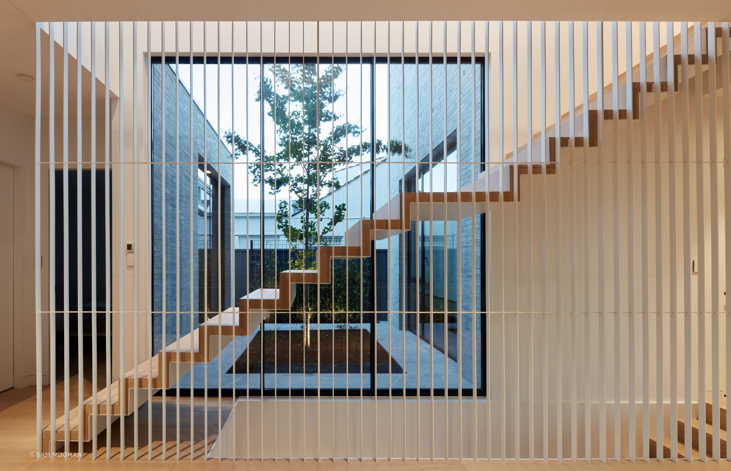 The suspended timber staircase with a battened steel balustrade lets the light flow through from the courtyard | Tennyson Residence by Enzo Caroscio Architects