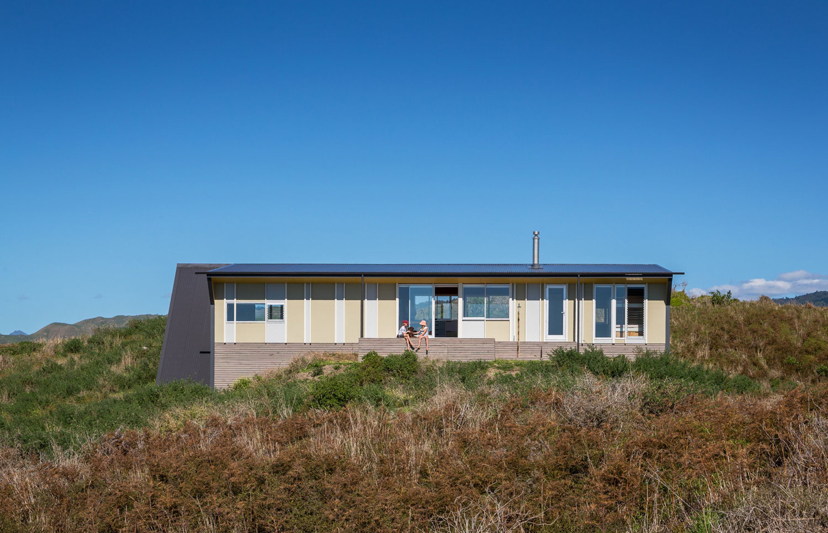 Te Horo Bach by Parsonson Architects is a small economically planned fibro and batten-clad building that has its design roots partly in the New Zealand bach tradition, with an explorative use of form, colour and material. Photograph by Paul McCredie.