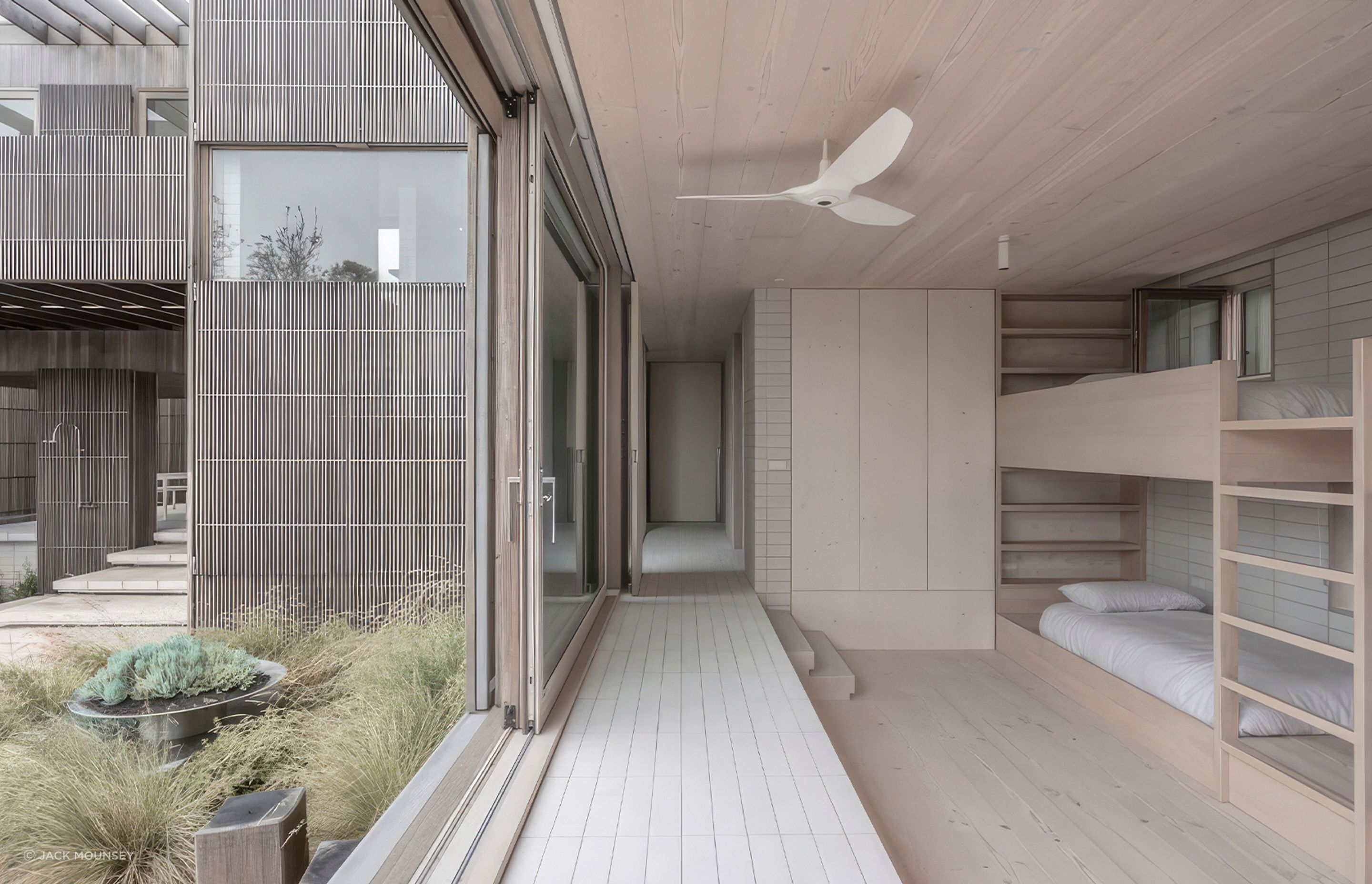 Instead of fenced-in yards, Bermagui Beach House blends together layers of sculpted landscapes that emulate the look of sand dunes and peripheral outdoor spaces.