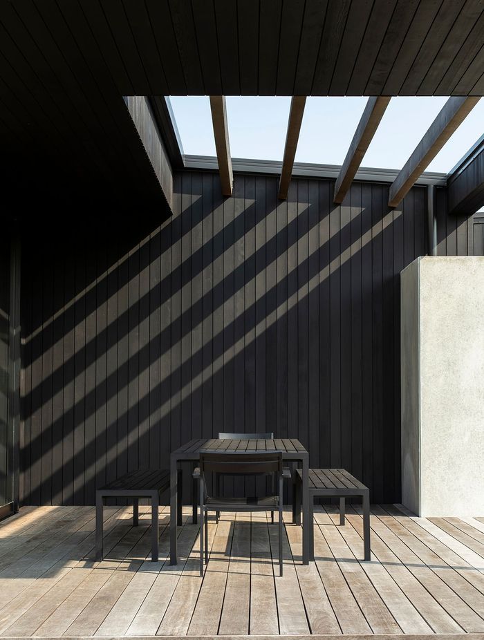 At Vineyard House, shadows from the overhead louvres stripe the timber wall of the outdoor room.