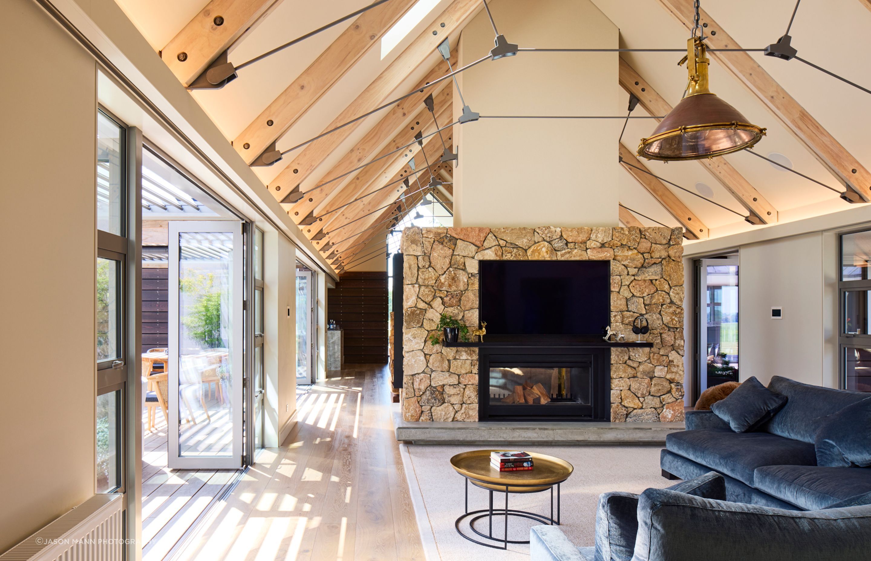In the interior, the stone-clad fireplace matches beautifully with the honey tones of the oak floor and timber rafters.