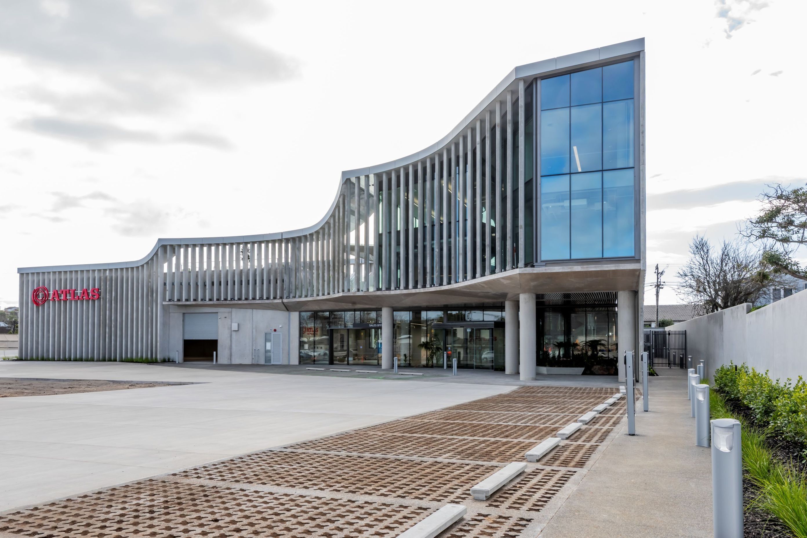 “Enveloping the fully-glazed office spaces, a veil of concrete fins serves a dual purpose: providing essential sun shading while creating a subtle barrier between the work environment and its industrial surroundings.”