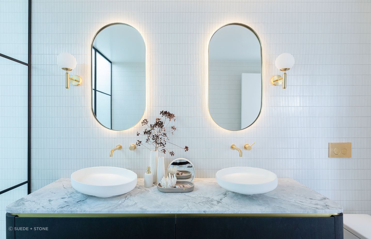 The exquisitely designed Oakpark bathroom interiors with warm toned backlit mirrors creates a cosy atmosphere