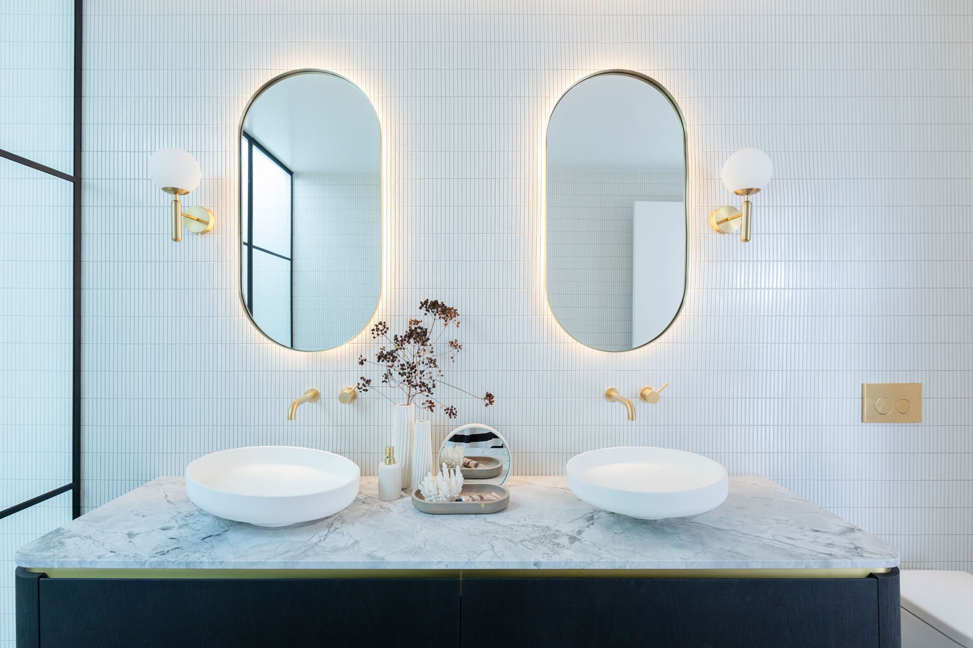 The exquisitely designed Oakpark bathroom interiors with warm toned backlit mirrors creates a cosy atmosphere
