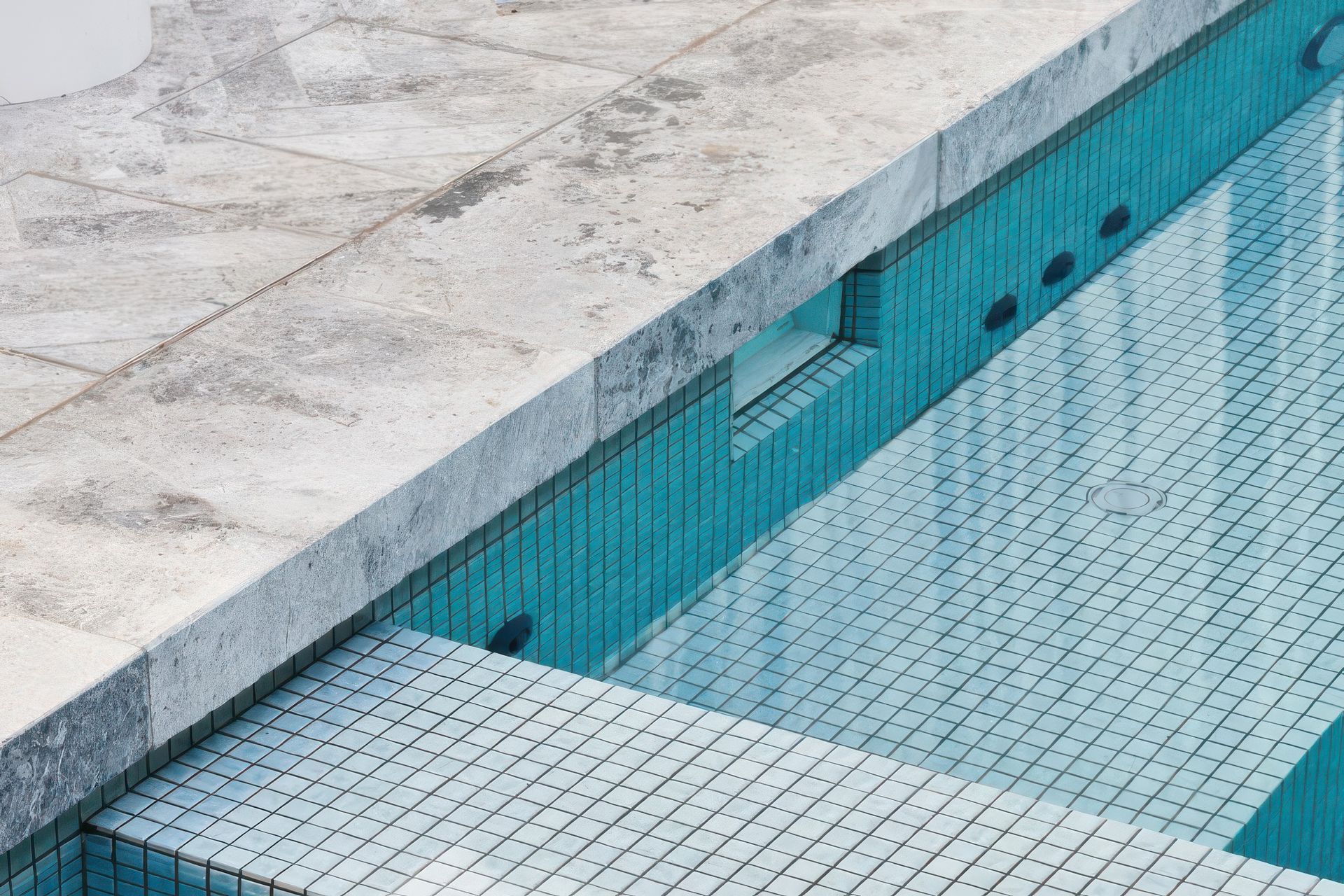 Tundra paving with Amano Ice Blue 25×25 Pool Tiles. Pool by Franklin Pools.