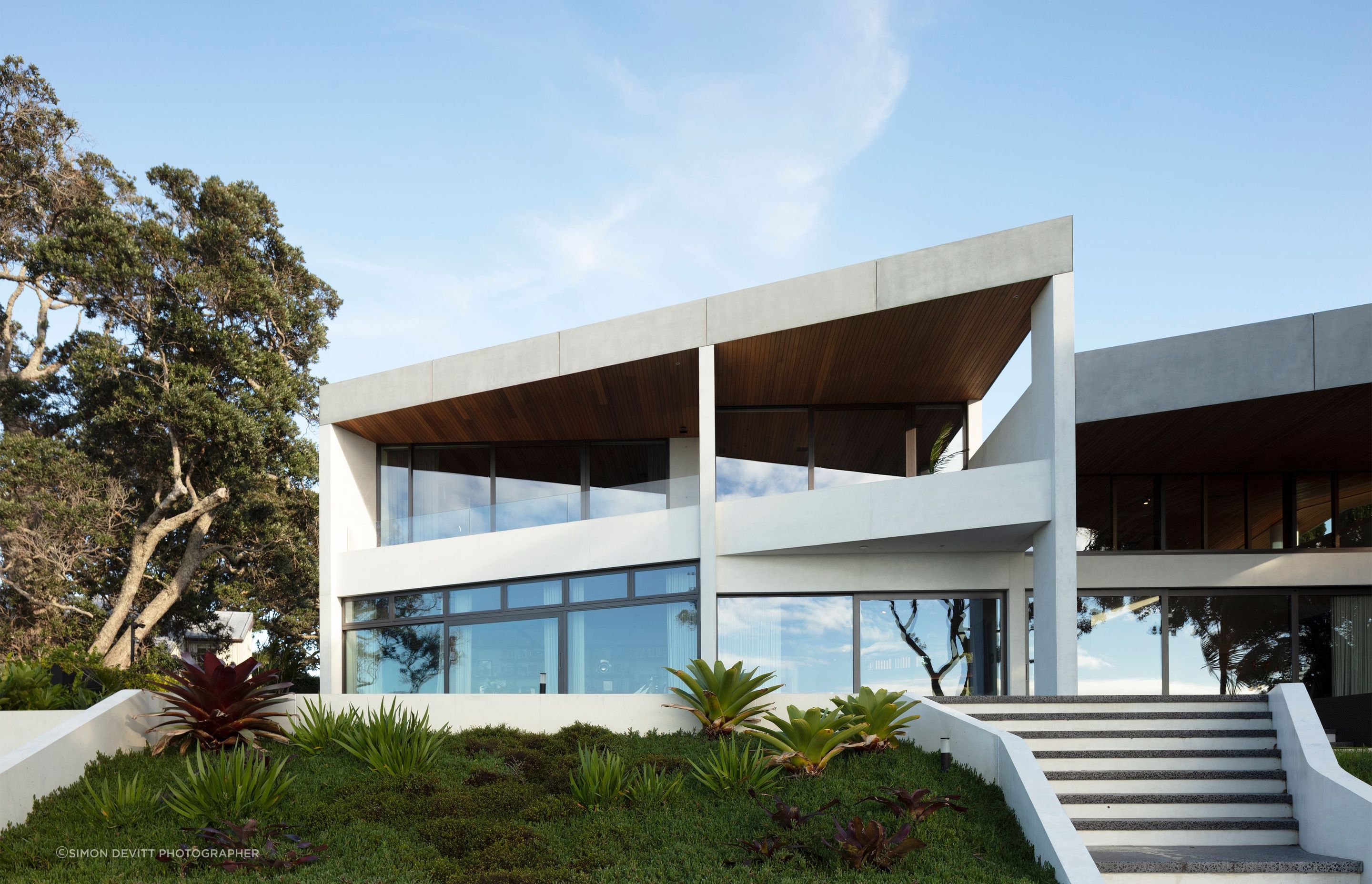 The Clifftops home by Bossley Architects connects beautifully to its site, through a sculptural beauty expressed through dyed white concrete forms.