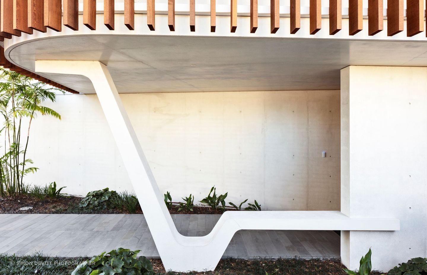 A striking sculptural element in white concrete provides a perfectly serene spot to sit and take off your shoes at the entrance of Clifftops house.