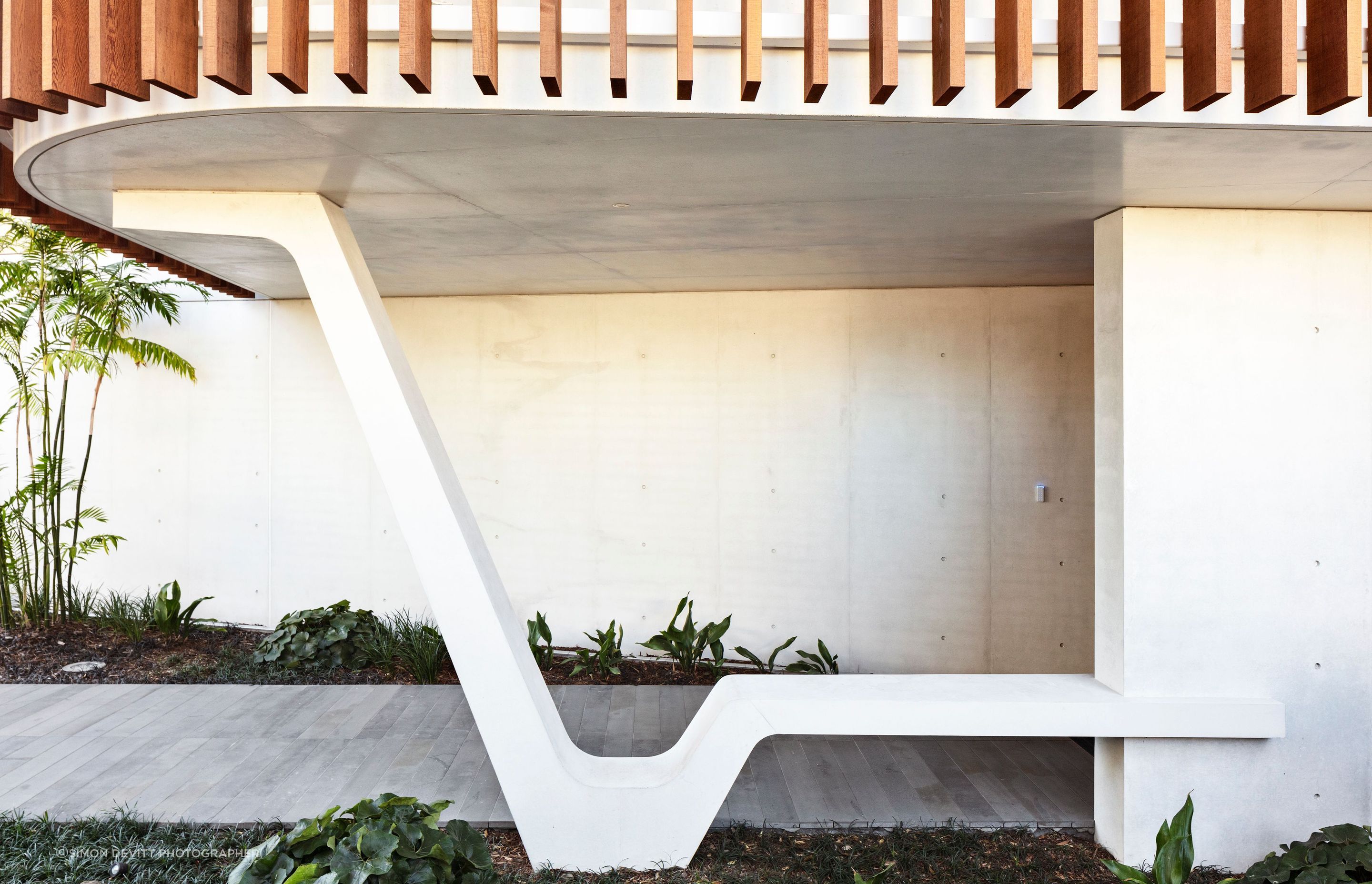 A striking sculptural element in white concrete provides a perfectly serene spot to sit and take off your shoes at the entrance of Clifftops house.