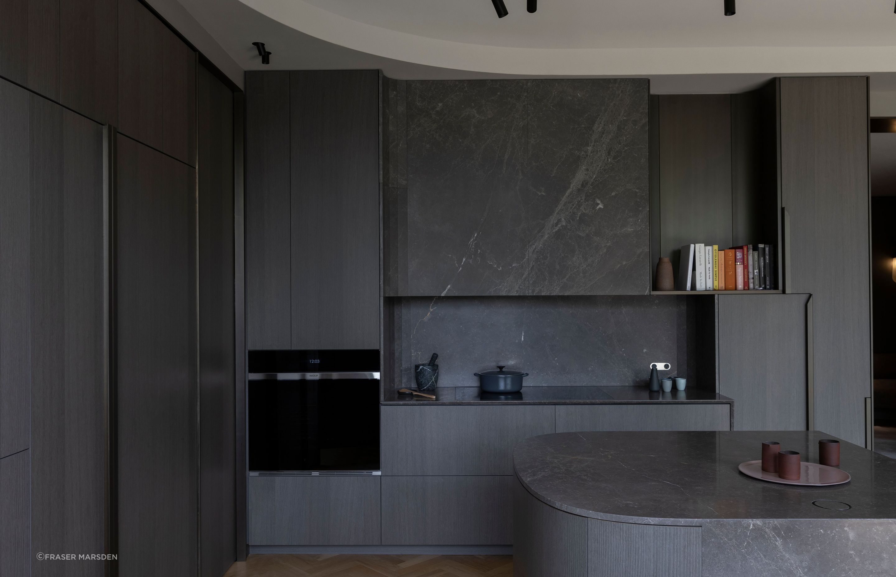 A play masculine and feminine with the blending of curves combined with sharp rectilinearity and a palette of dark, warm materials.