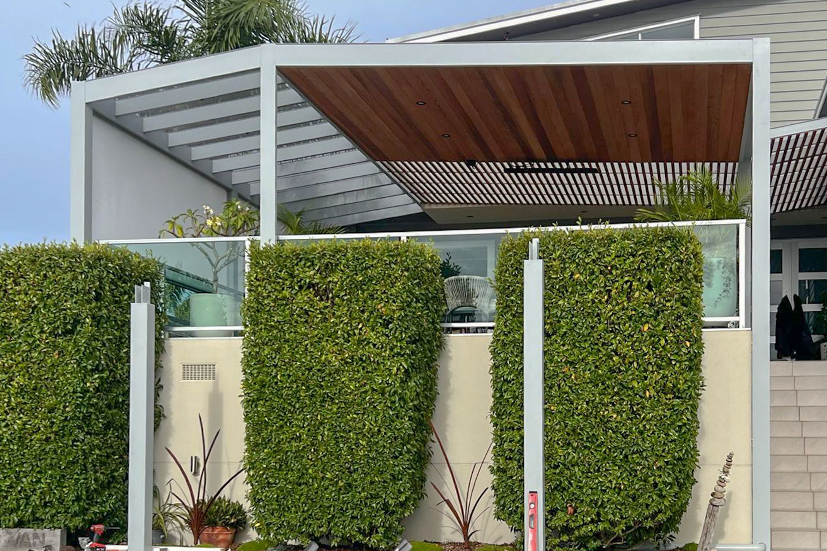 Pergolas can be custom designed to imitate the roofline and aesthetic of the home. This pergola by Sanctuary Pergolas features timber ceiling cladding and lighting that creates a seamless flow from indoors to outdoors.