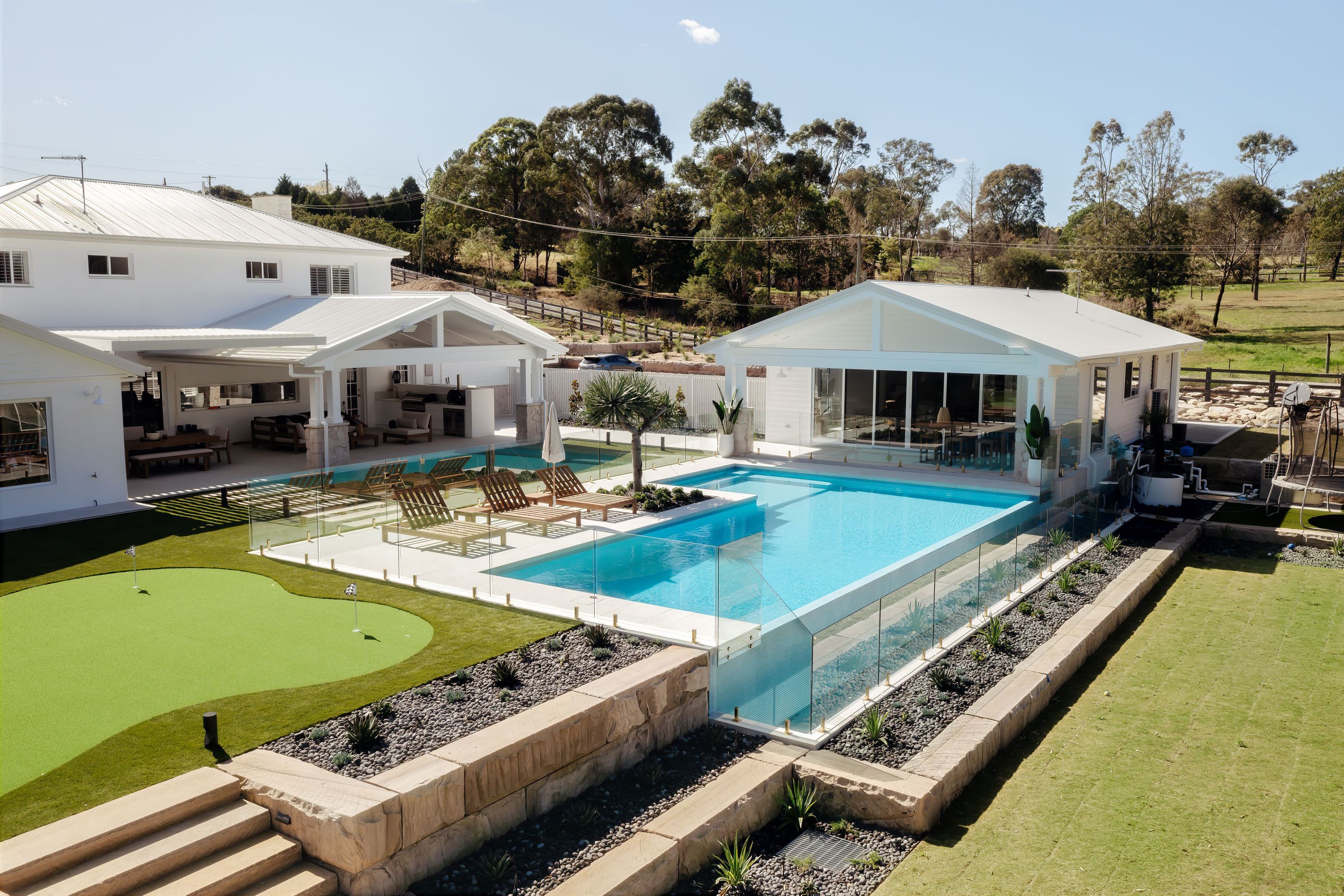 This stunning rural property features unique landscaping and frameless glass by Glazed Co around the pool, creating a resort-like vibe.