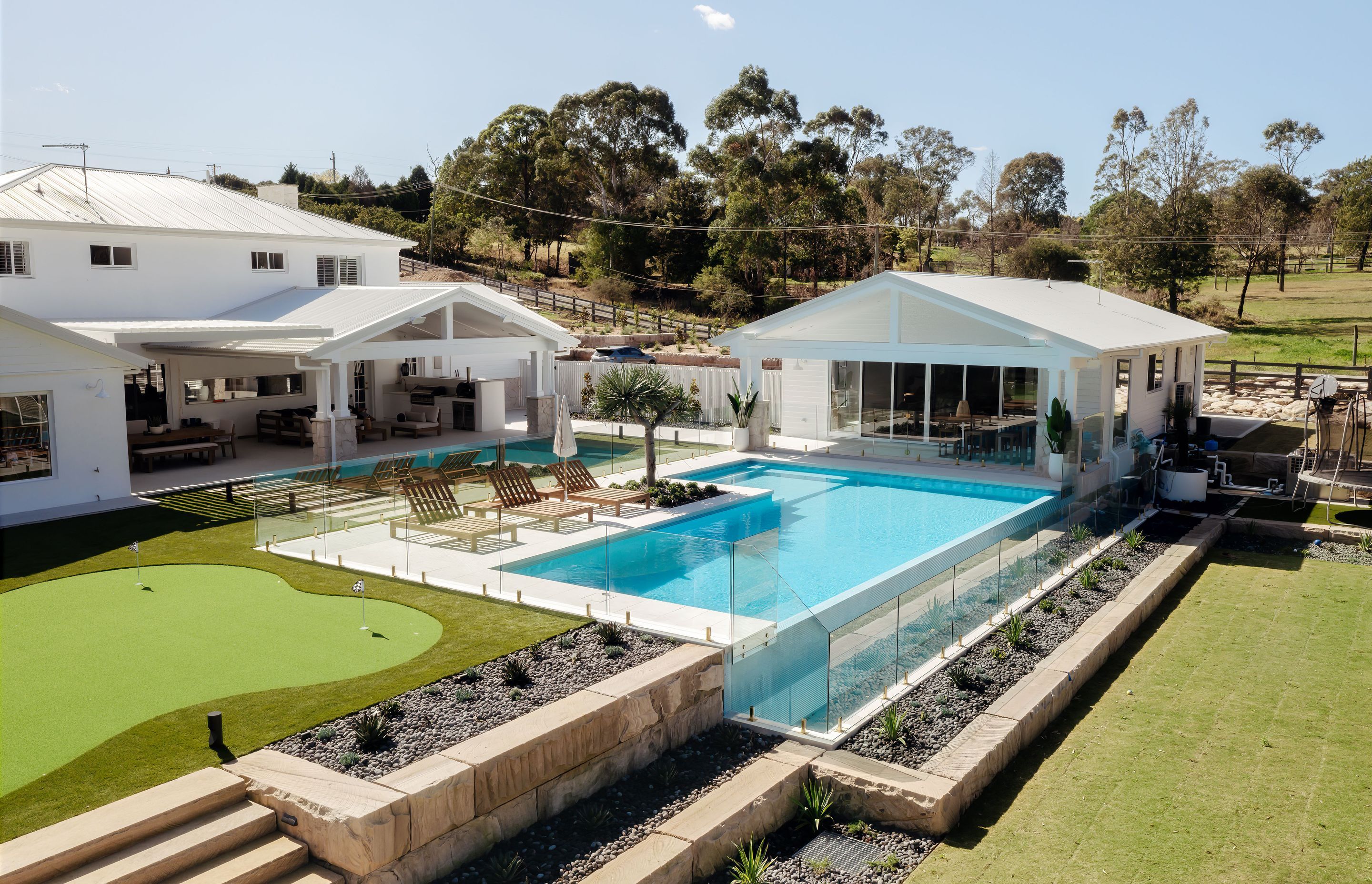 This stunning rural property features unique landscaping and frameless glass by Glazed Co around the pool, creating a resort-like vibe.