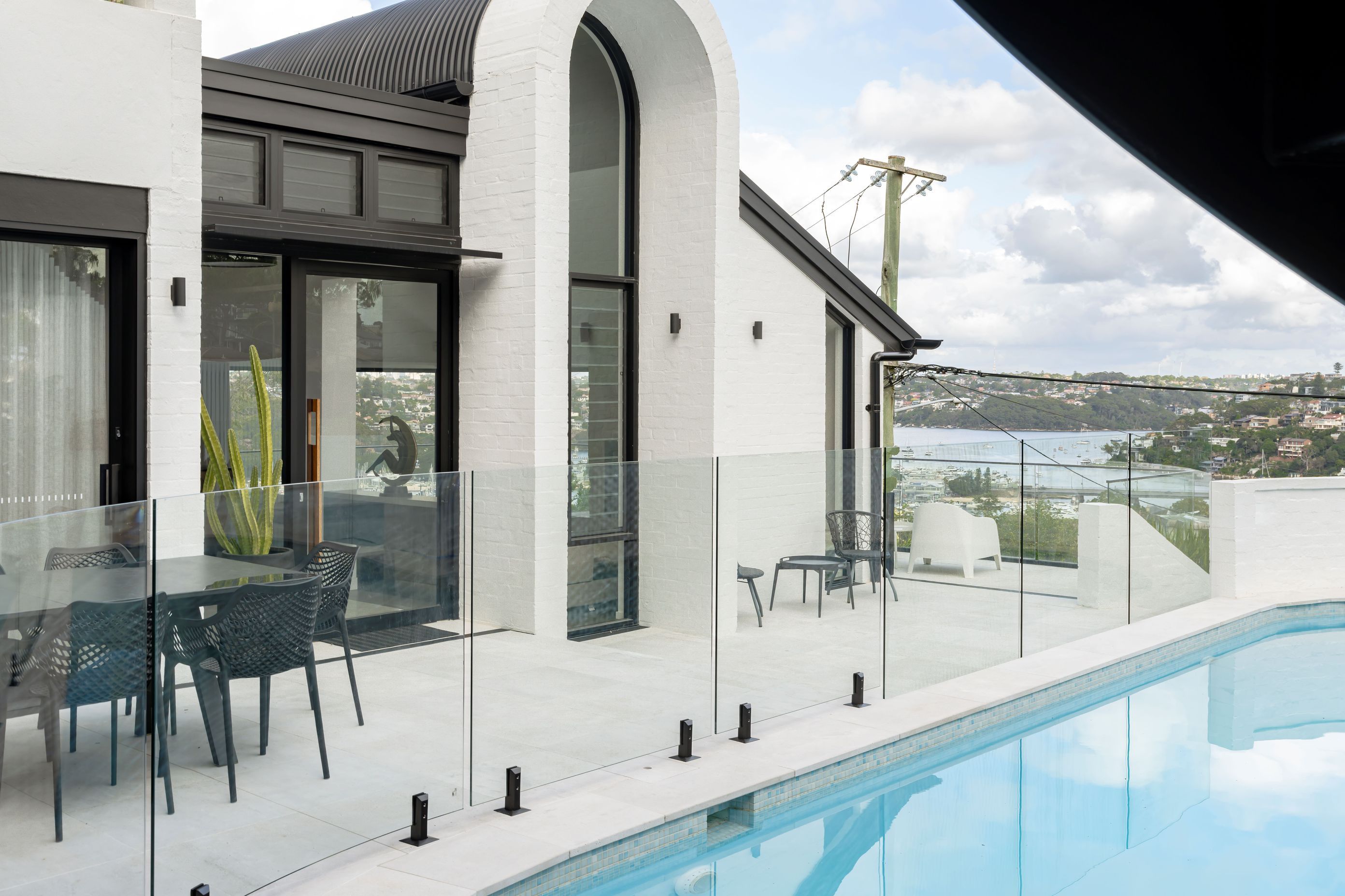 The strong monochromatic statement of this home is reflected in the pool glazing and black hardware by Glazed Co.