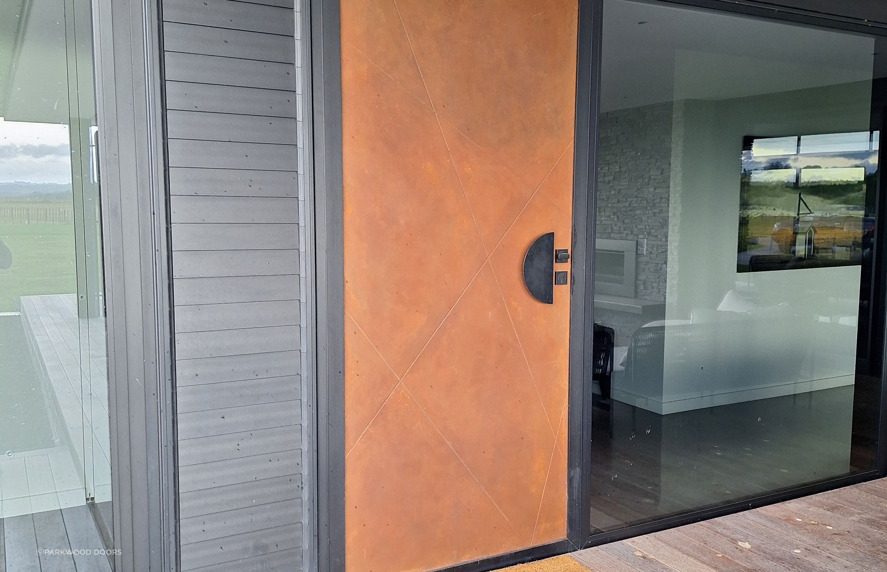 This composite door by Parkwood Doors is painted in a rustic finish to look like Corten steel.