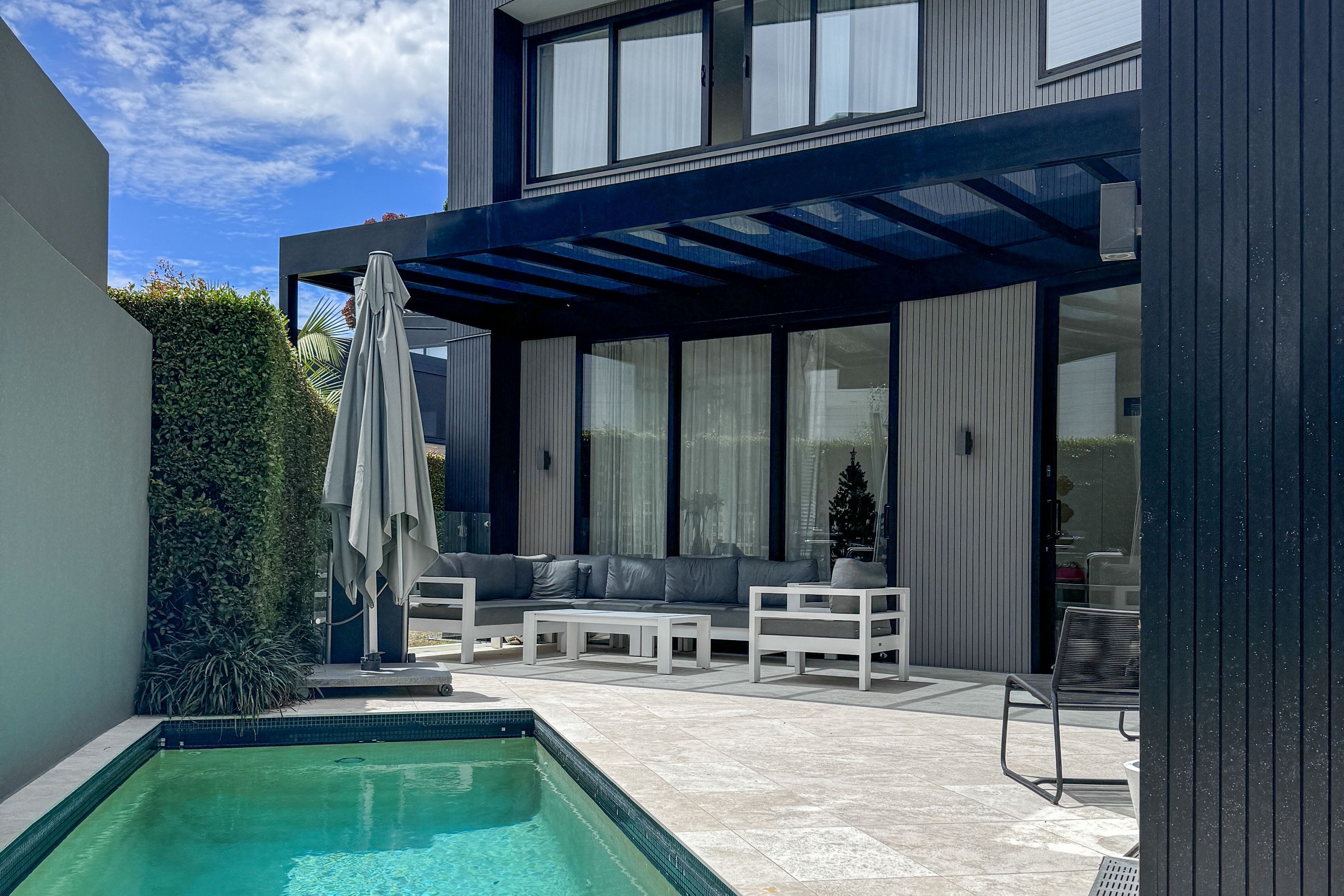 A dramatic black pergola creates a sheltered outdoor entertainment space.
