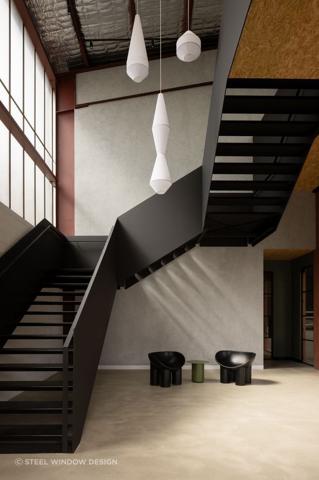The steel staircase between levels becomes part of the narrative.