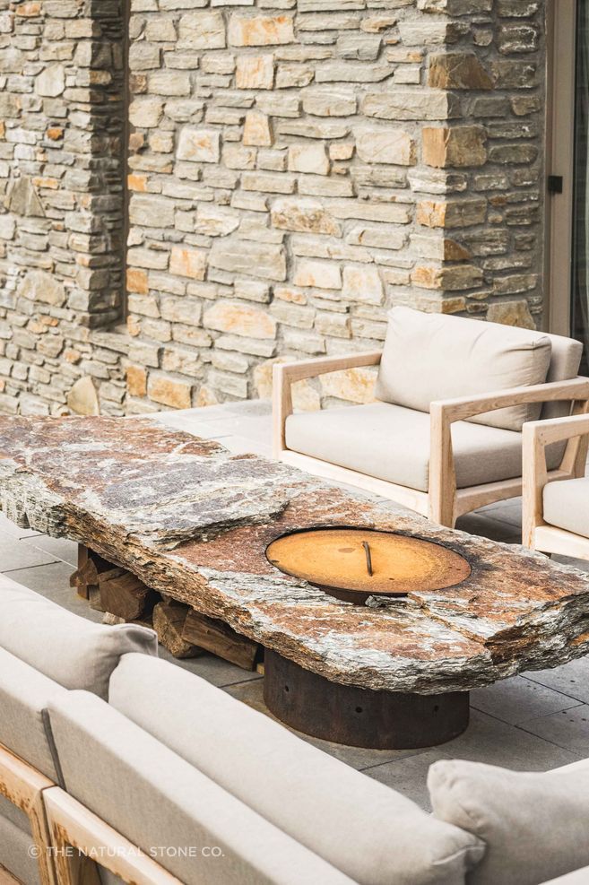 A schist wall grounds the home and anchors the schist firepit, both by The Natural Stone Co.