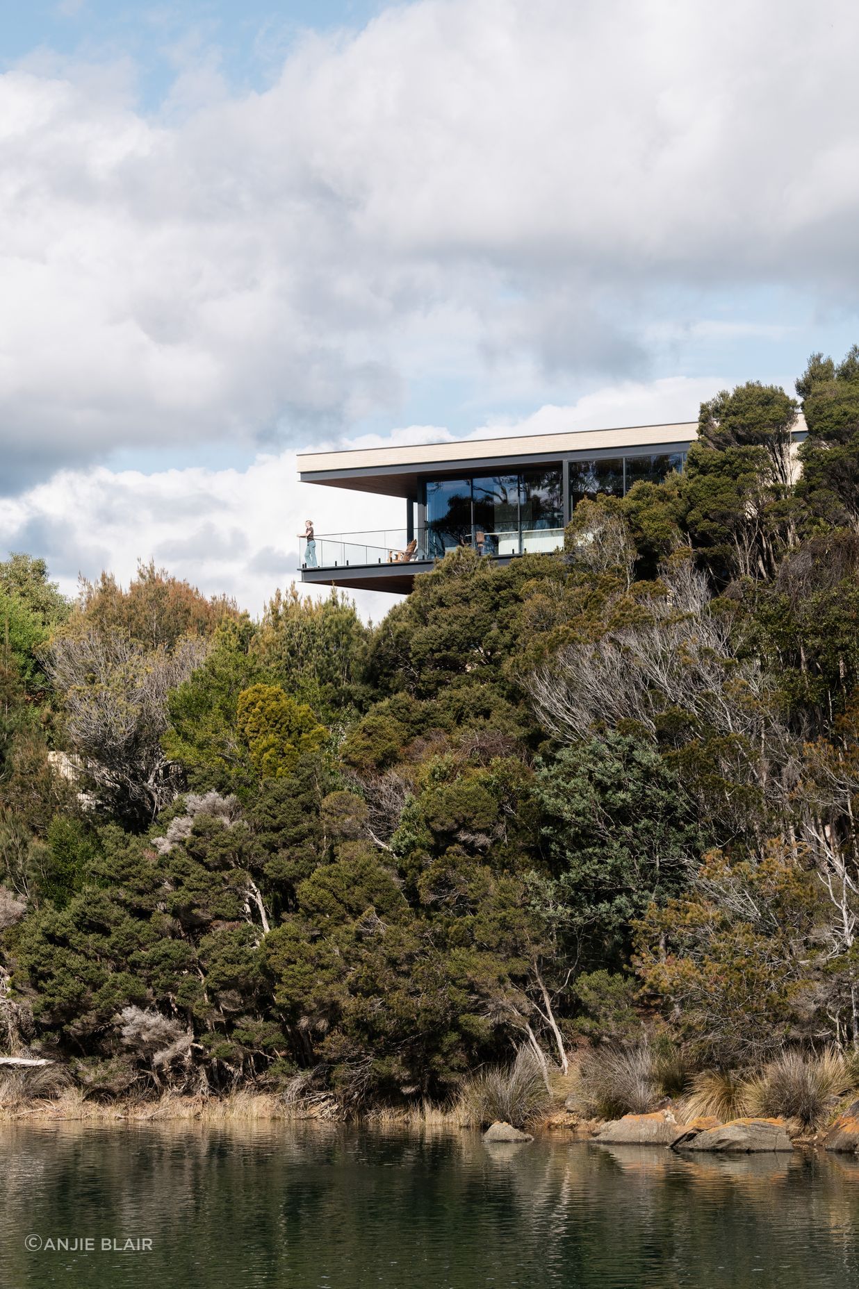 Perched above the estuary, the home maximises its connection with the surrounding nature with extensive glazing.
