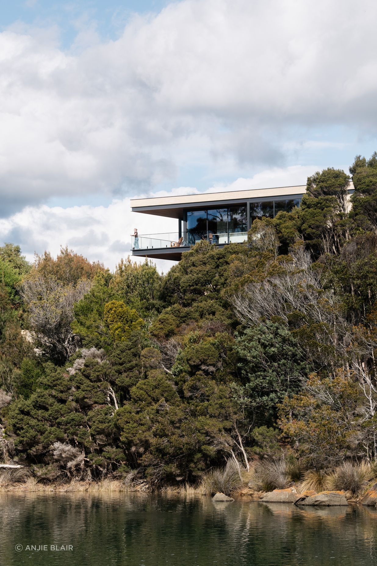 Perched above the estuary, the home maximises its connection with the surrounding nature with extensive glazing.