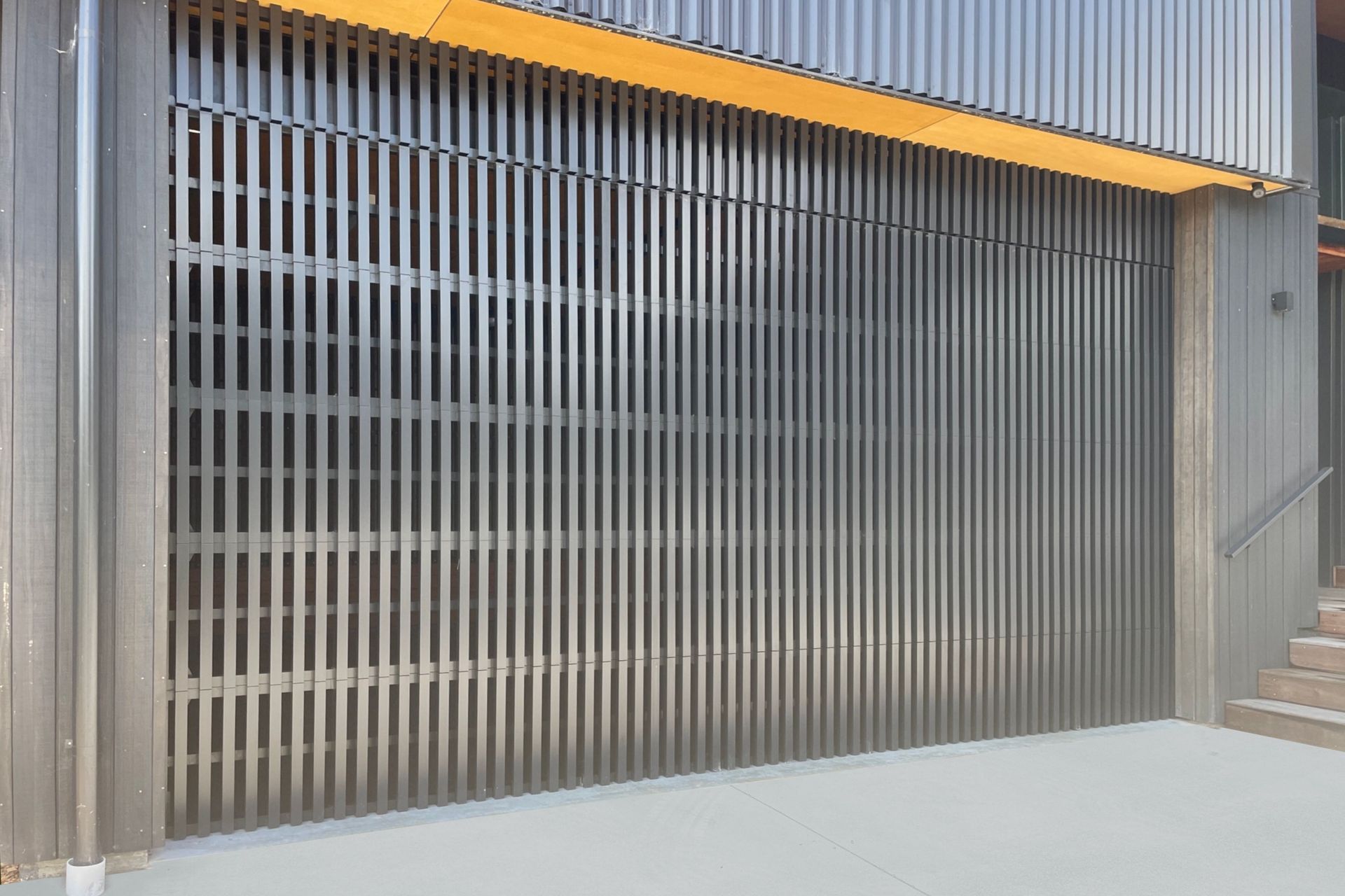 A custom batten ventilated garage door installed at a workshop in Whangamatā.