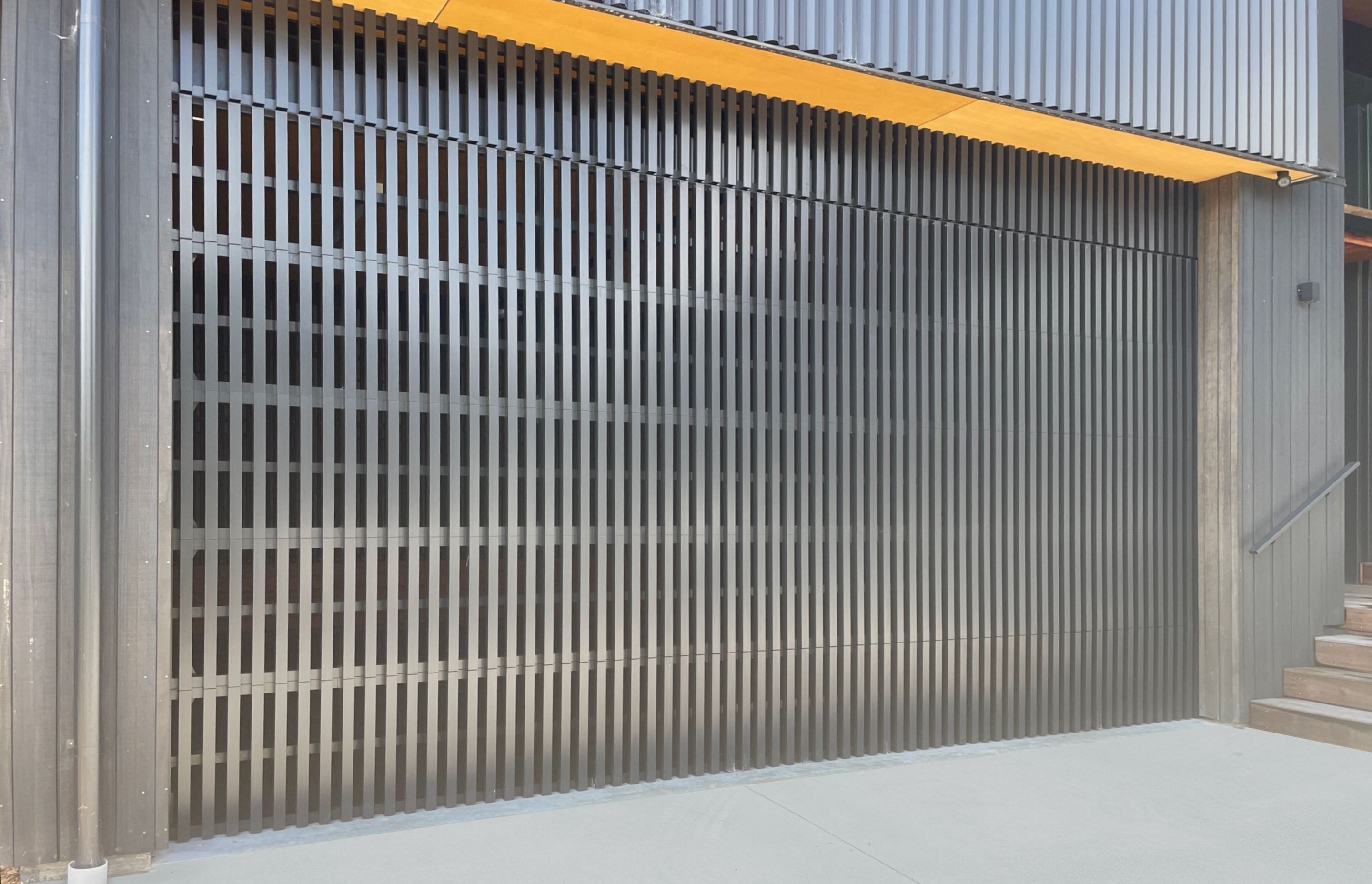 A custom batten ventilated garage door installed at a workshop in Whangamatā.