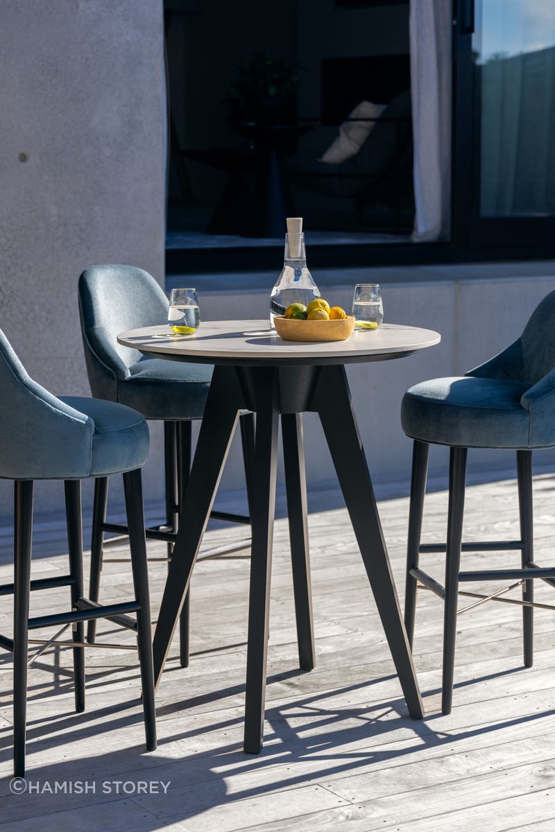 The Silhouette Bar Stool is paired here with the Iris Porcelain Poseur Table for a chic outdoor setting.