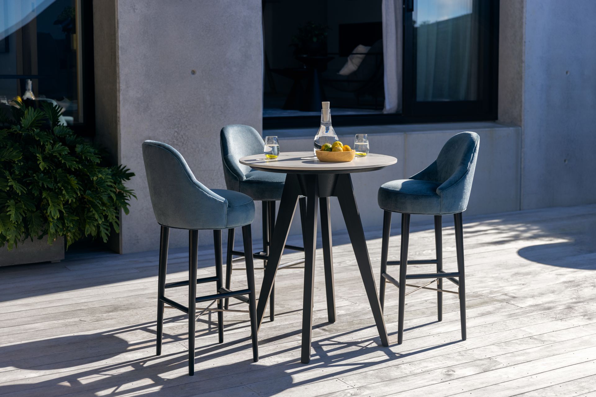 The Silhouette Bar Stool is paired here with the Iris Porcelain Poseur Table for a chic outdoor setting.