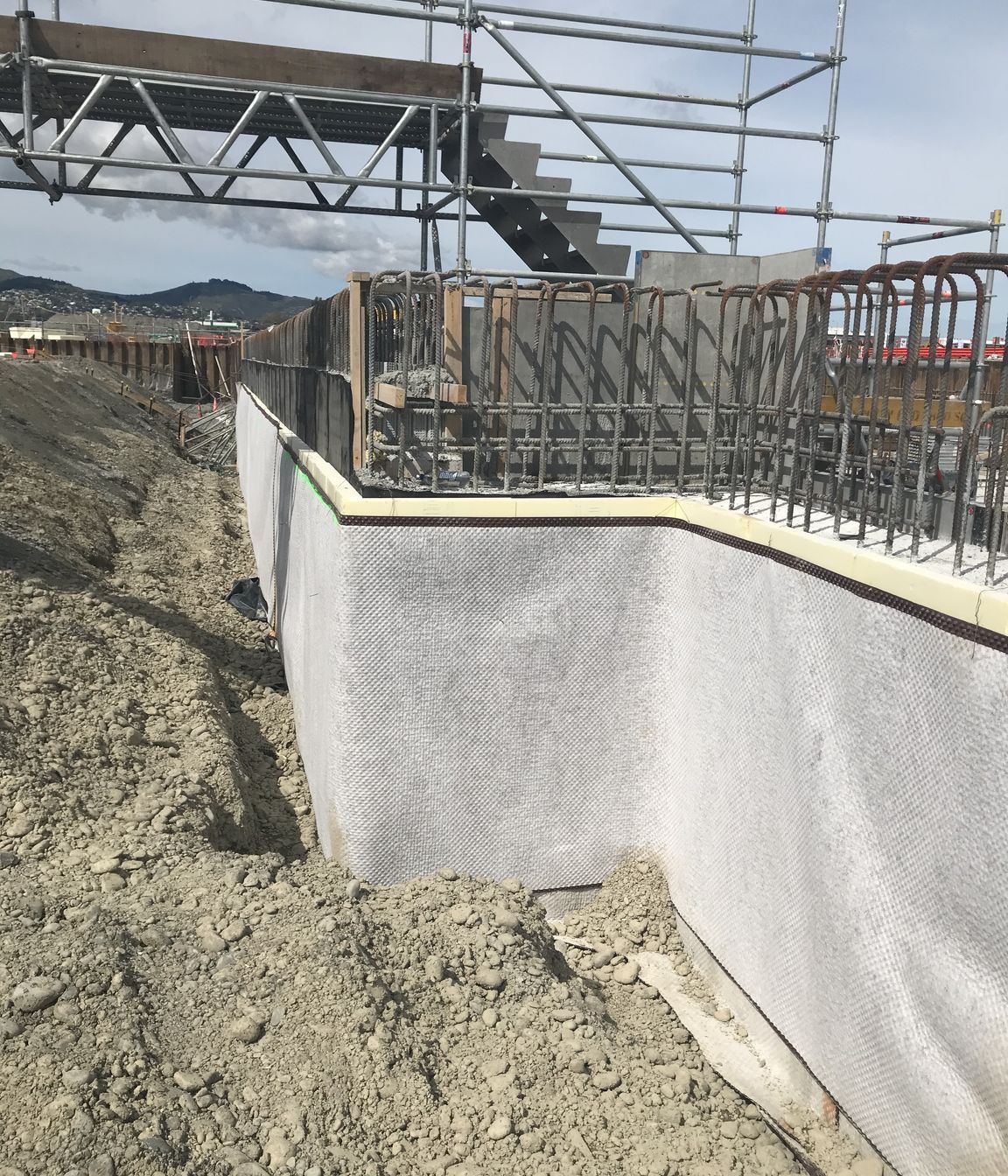 Vertical underground tanking and thermal insulation protected by a drainage and protection mat.