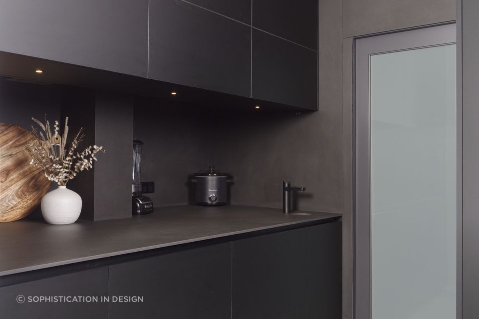 Appliances disappear within the dark spashback and bench.