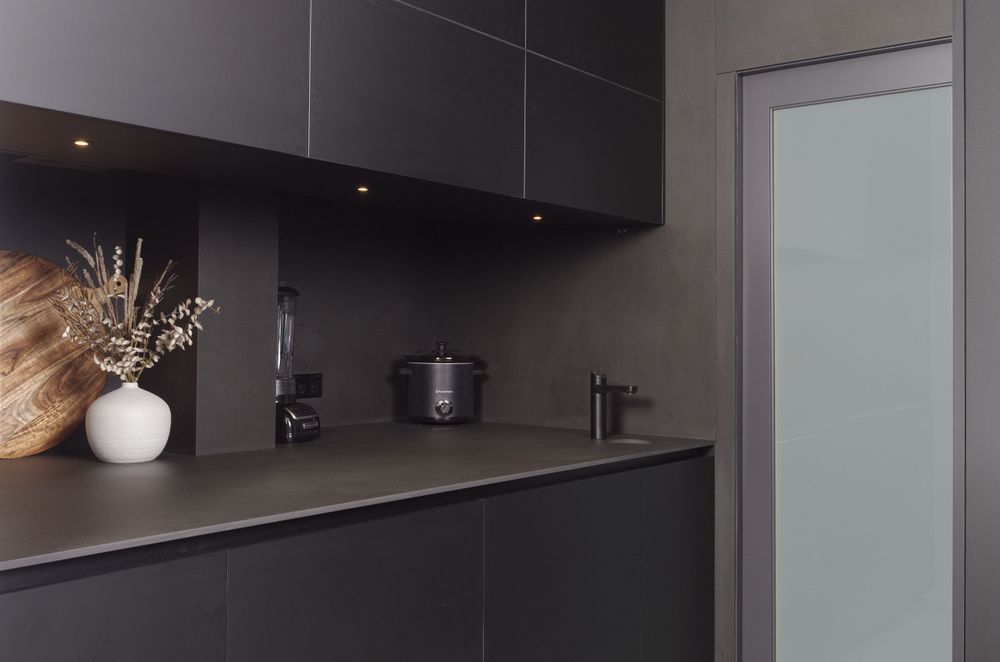 Appliances disappear within the dark spashback and bench.