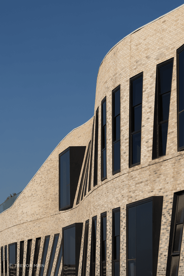 The textured façade of Petersen bricks forms a curved veil.