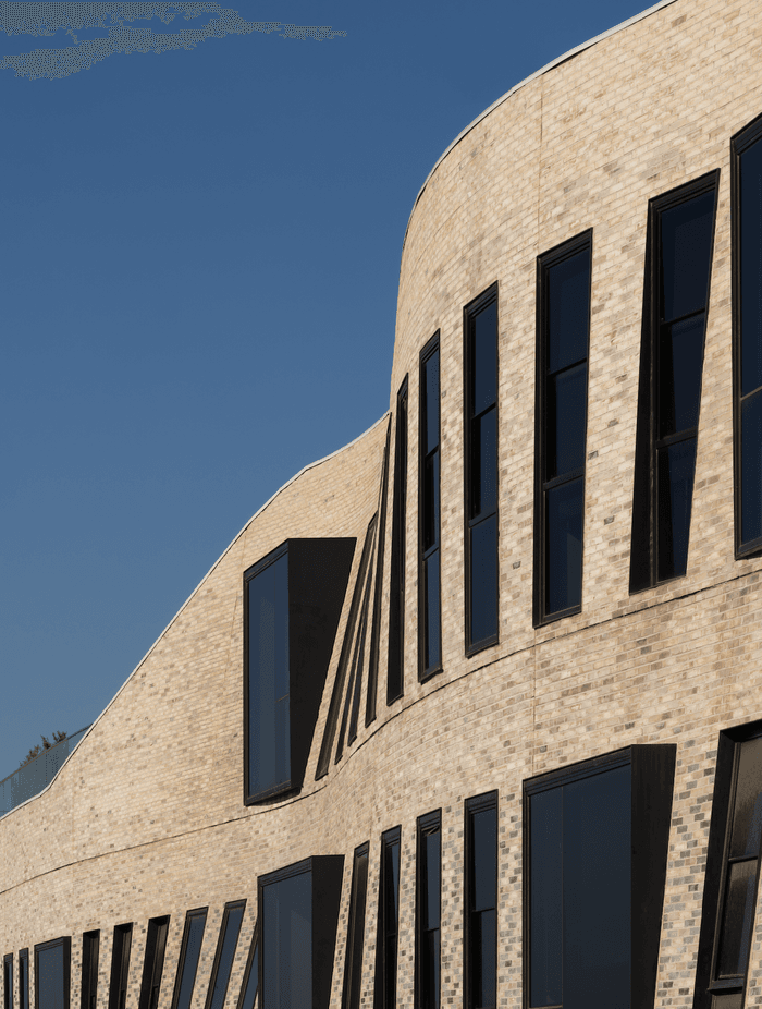 The textured façade of Petersen bricks forms a curved veil.