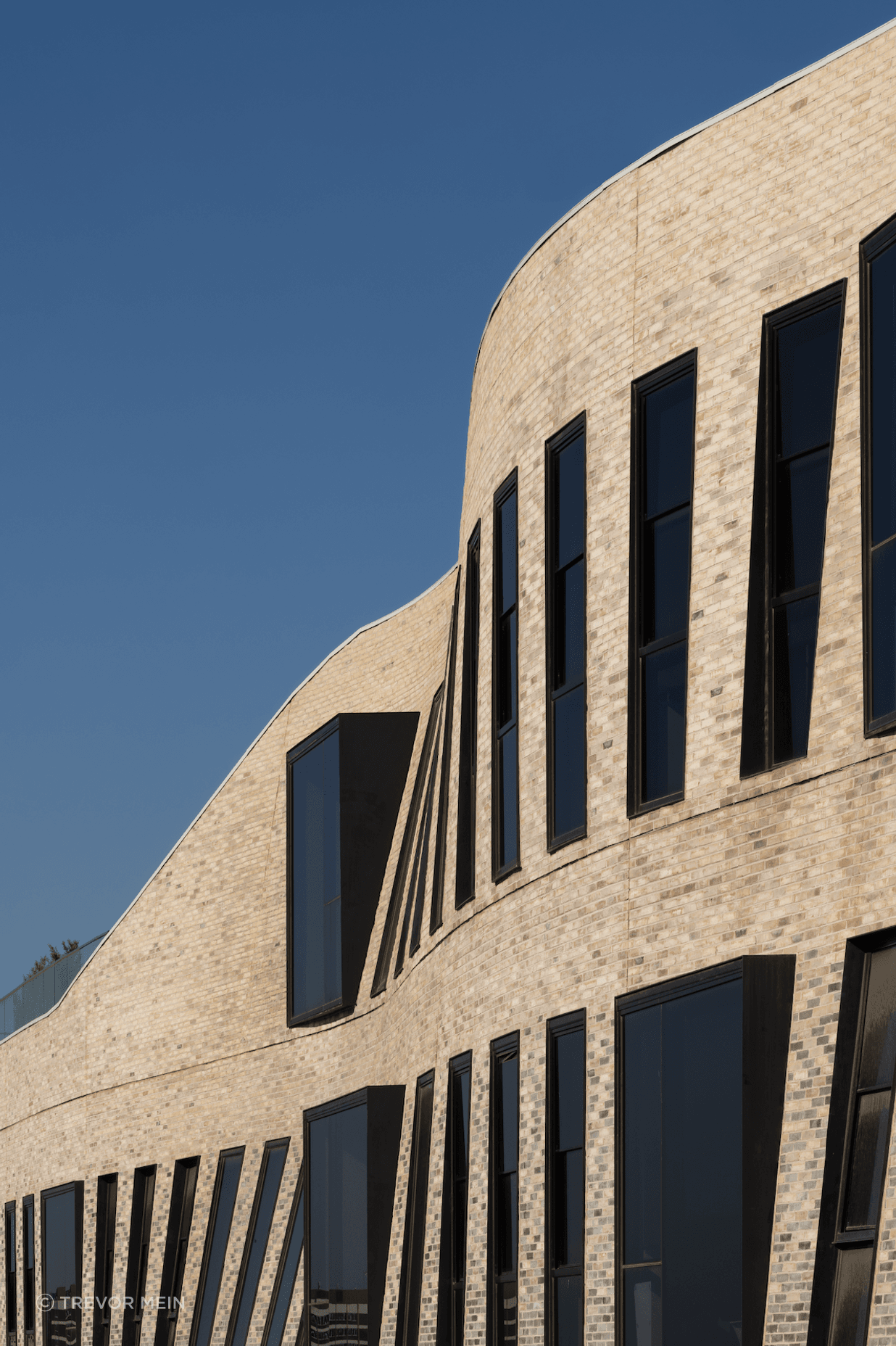 The textured façade of Petersen bricks forms a curved veil.
