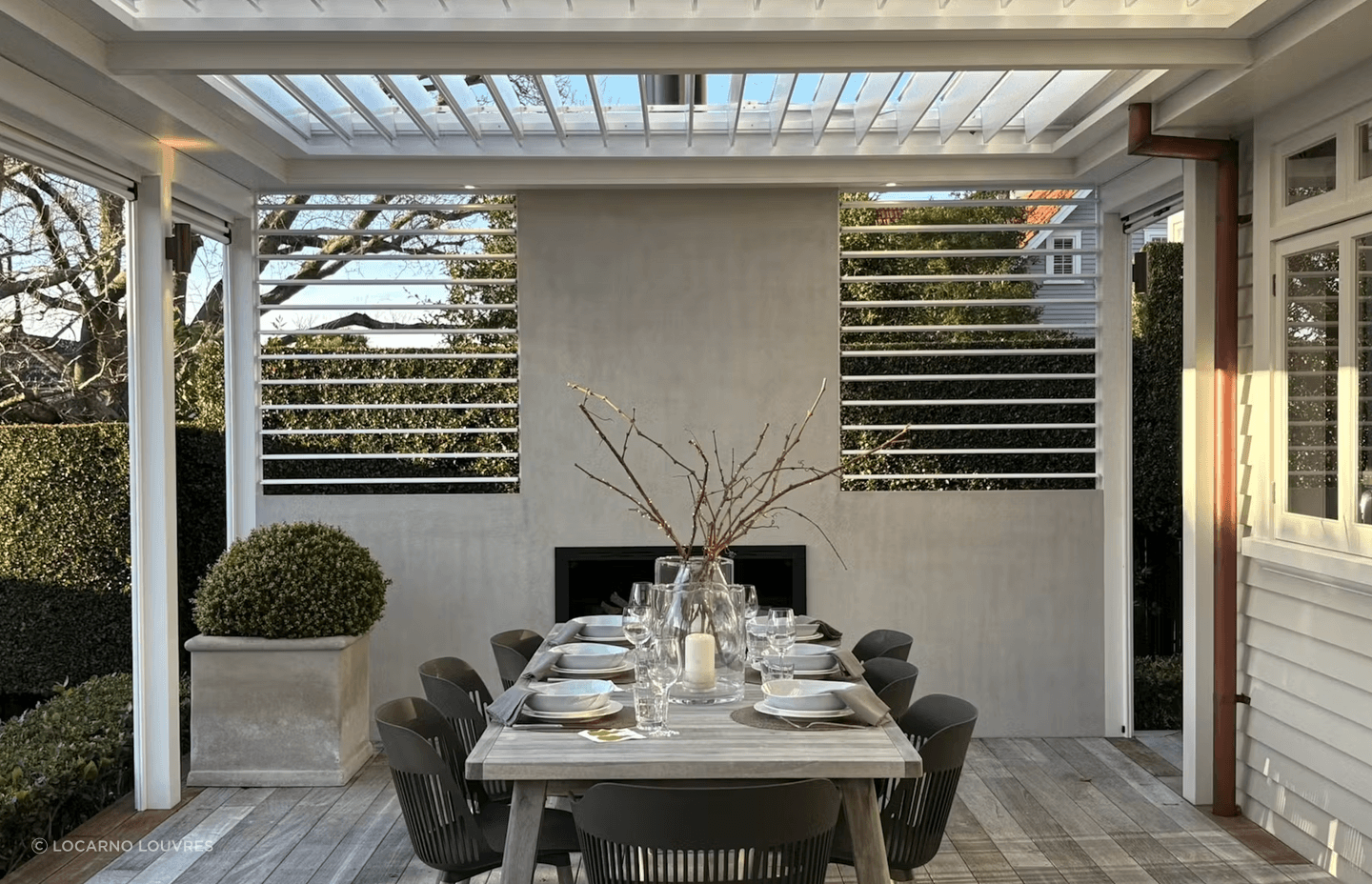The pergola incorporates four motorised panels of The super fine profile RLS200 louvres can be closed to provide shelter or opened to maximise light in the adjacent kitchen/living rooms. Two panels of manually adjustable RL130 screens add the finishing touch on either side of the plastered chimney.