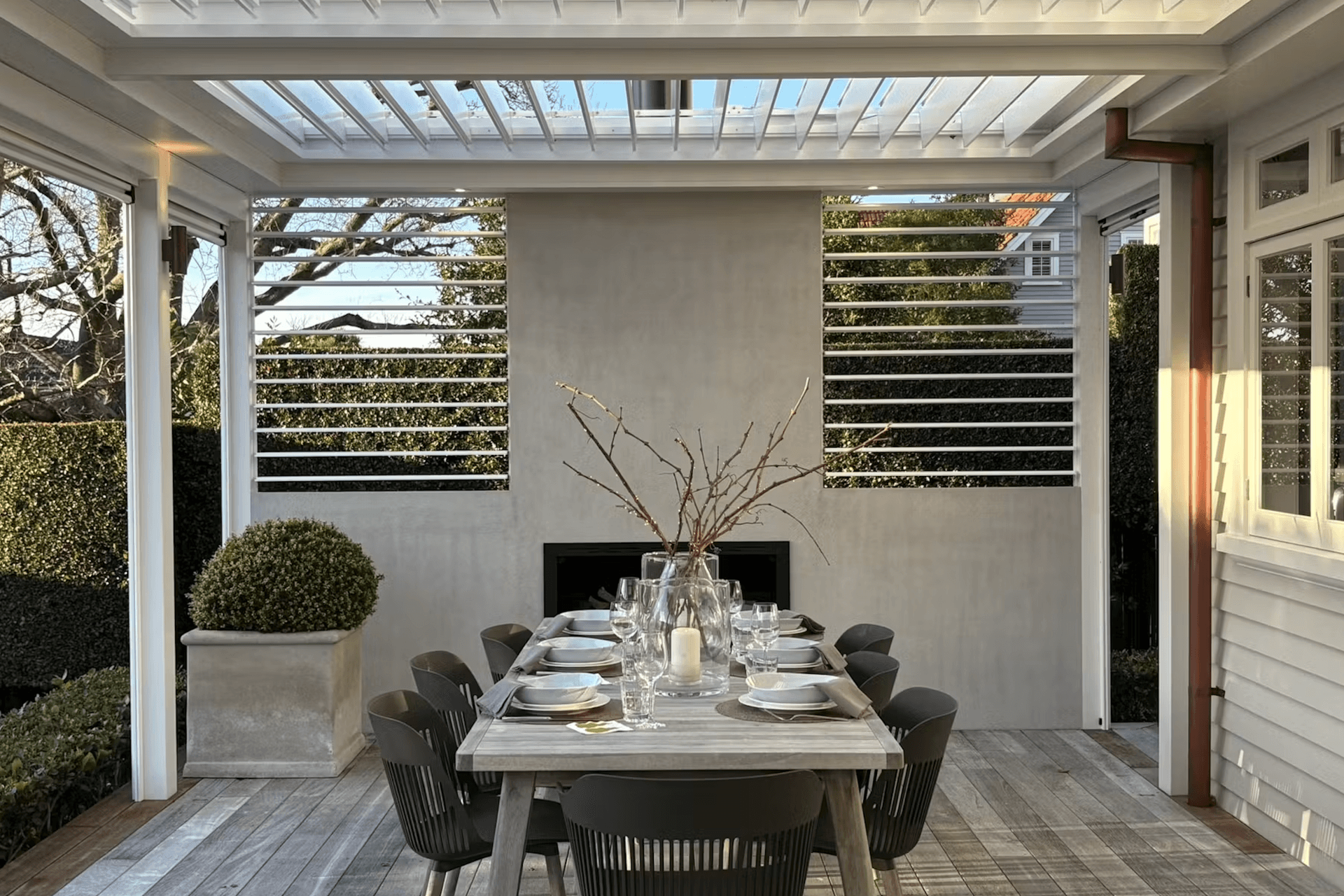 The pergola incorporates four motorised panels of The super fine profile RLS200 louvres can be closed to provide shelter or opened to maximise light in the adjacent kitchen/living rooms. Two panels of manually adjustable RL130 screens add the finishing touch on either side of the plastered chimney.