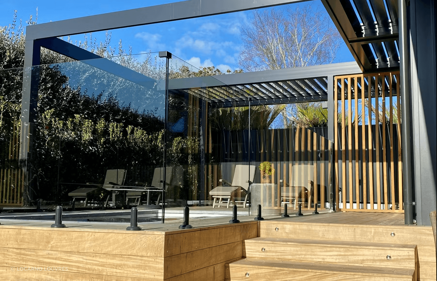Motorised RLS200 louvres, which infill part of the pergola, provide a sheltered area alongside the pool.