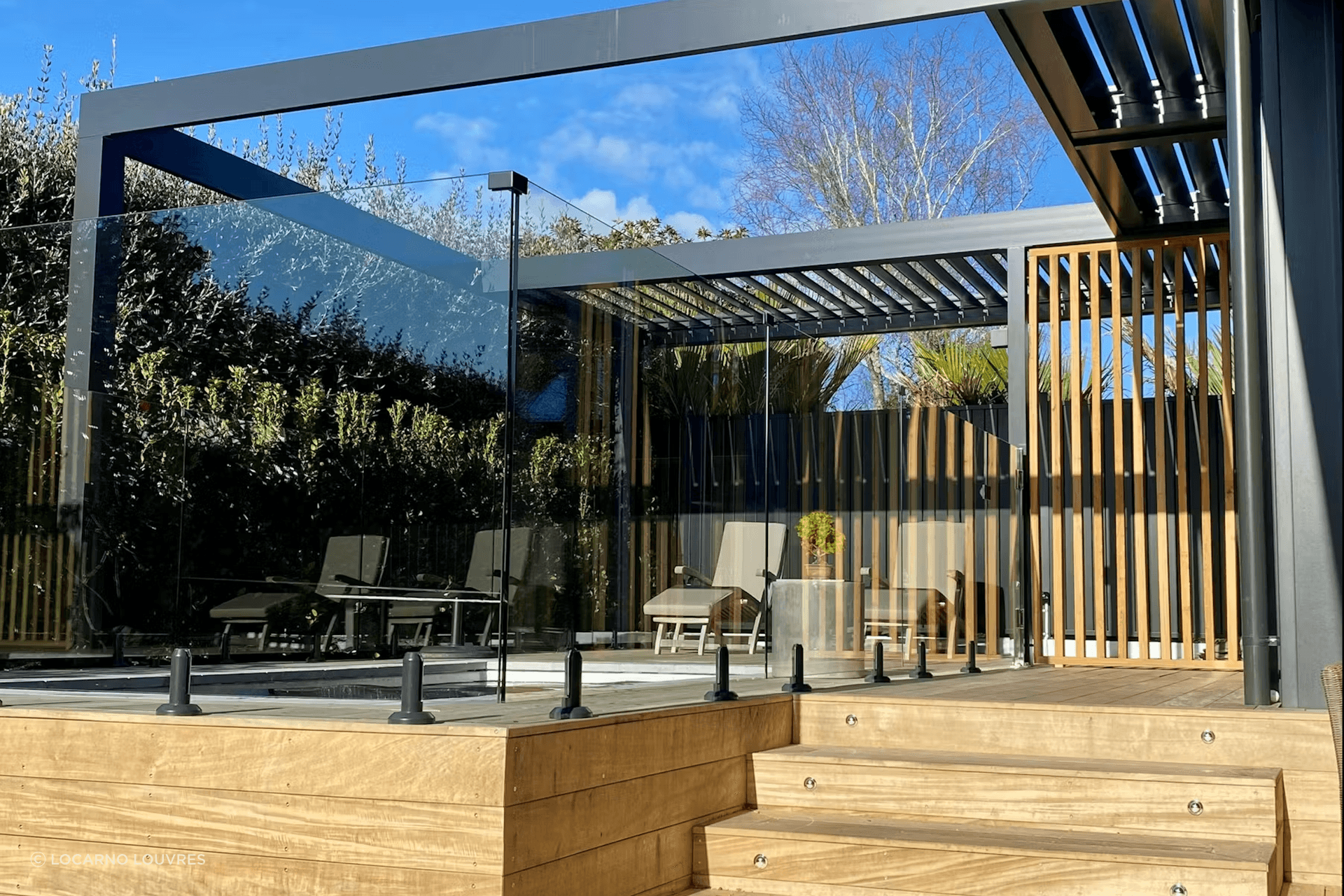 Motorised RLS200 louvres, which infill part of the pergola, provide a sheltered area alongside the pool.