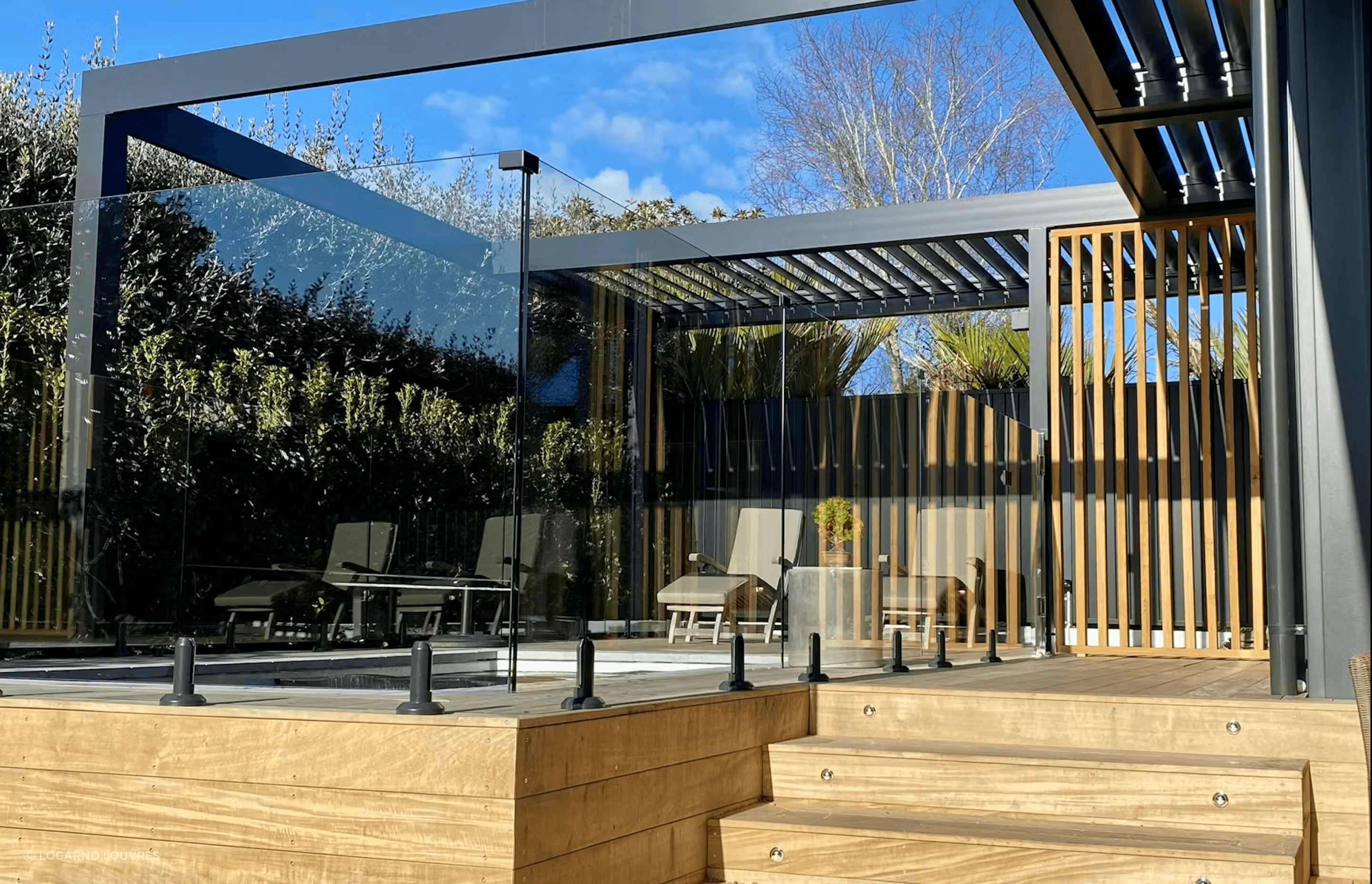 Motorised RLS200 louvres, which infill part of the pergola, provide a sheltered area alongside the pool.