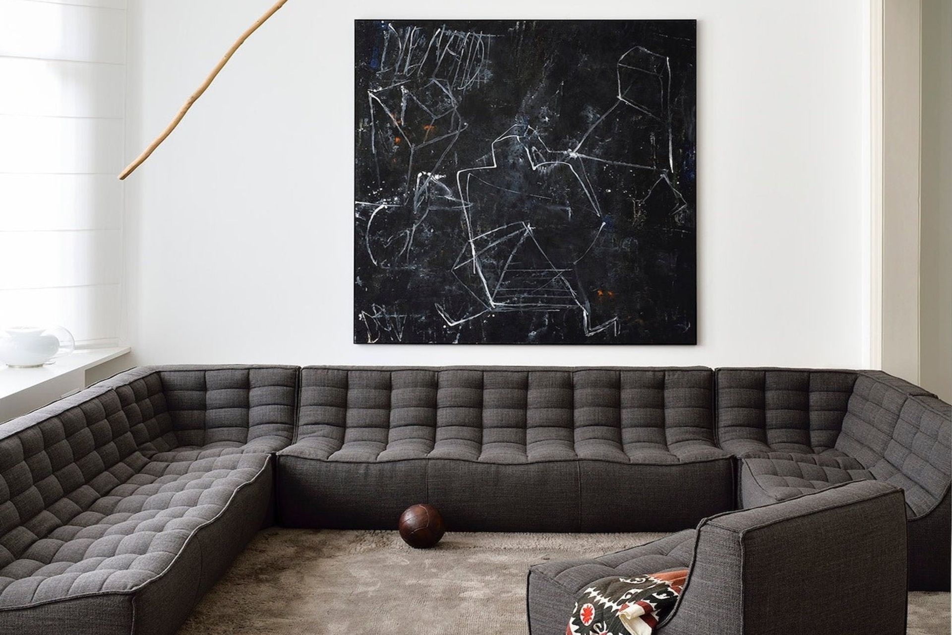 A clear white wall and distinct wall art provide a great backdrop to this dark grey corner sofa. Featured product: N701 Sofa Corner.