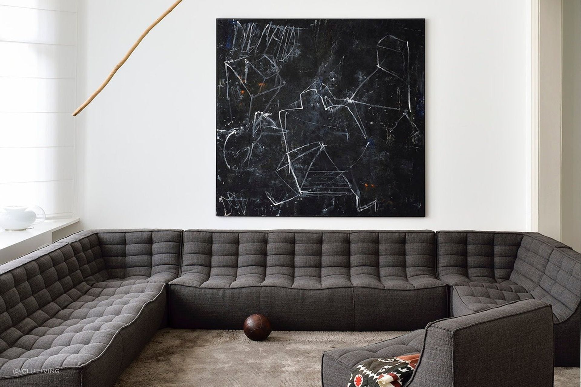 A clear white wall and distinct wall art provide a great backdrop to this dark grey corner sofa. Featured product: N701 Sofa Corner.