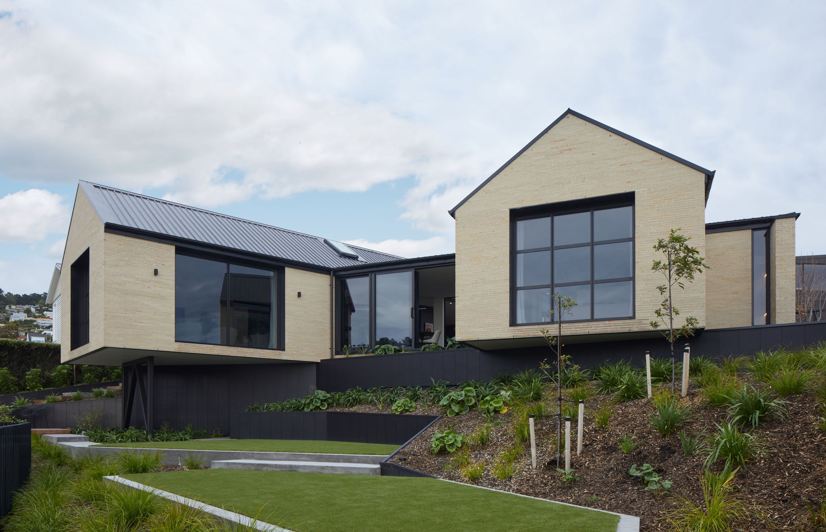 Split level landscaping and a cantilevered gable form showcase the beauty of using steep topography as a way of enhancing a home, in this DJ Hewitt new build.