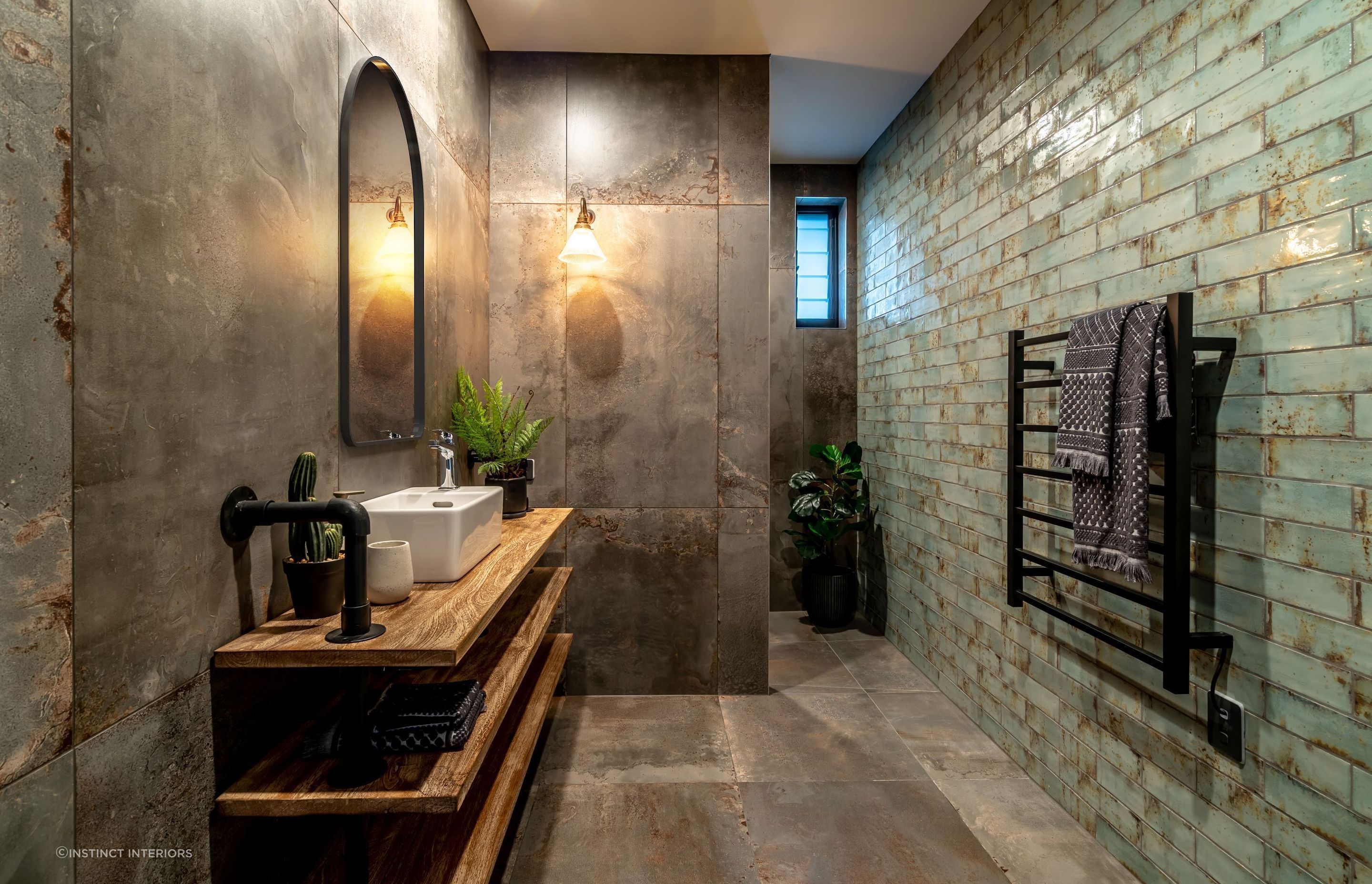 Textured tiles, exposed plumbing, timber shelving — just some of the raw materials incorporated in this bathroom in Alexandra.