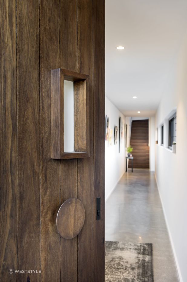 The door's rich wood grain and unique circular handle set the tone for the home's interior. Featured project: Alma by Weststyle