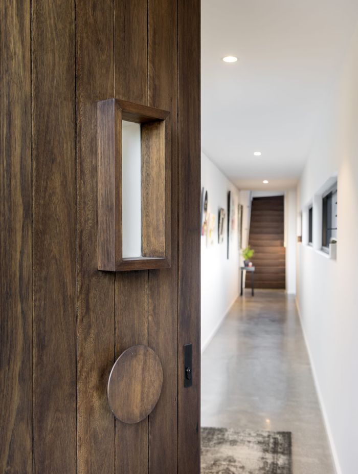 The door's rich wood grain and unique circular handle set the tone for the home's interior. Featured project: Alma by Weststyle