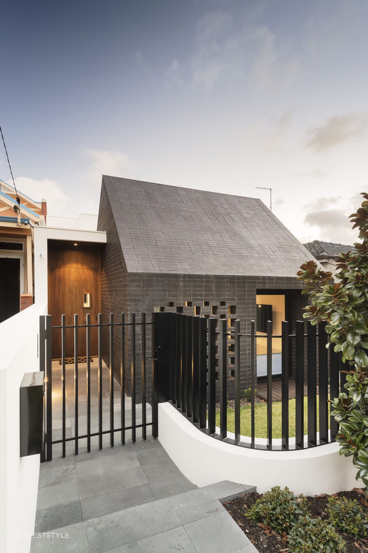 This home's side entrance is marked by a striking door that offers both privacy and intrigue. Featured project: Alma by Weststyle