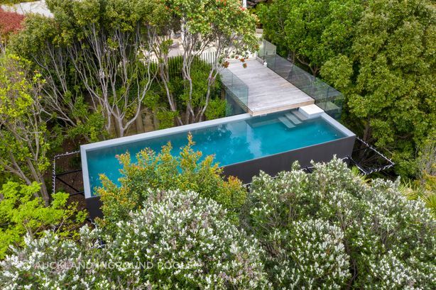 A custom built 10m x 3m pool with a volume of 45,000L is nestled among the tree tops in suburbia as part of a greater landscaping project to make good use of a redundant space.
