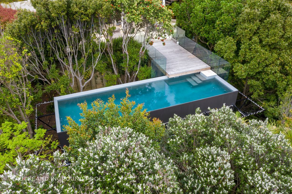 A custom built 10m x 3m pool with a volume of 45,000L is nestled among the tree tops in suburbia as part of a greater landscaping project to make good use of a redundant space.
